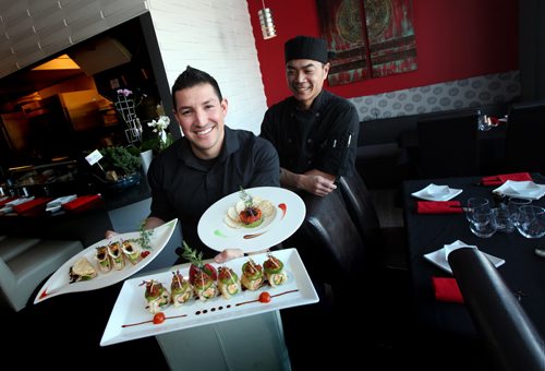 At home serving up home runs, former Goldeye Amos Ramon balances an armload of delicasies at his new endeavor "Fusian' Experience on Academy Road. Business Partner and Chef Chris Taing (right) formerly of Asahi who's keeping an eye on the ball player's table manners. See Melissa Martin's story. February 11, 2015 - (Phil Hossack / Winnipeg Free Press)