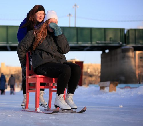 Visiting from North Dakota on a school trip, Kaitlyn Aarseth pushes her friend Atlanta Lehfeldt on the red chairs of the Recycling Words Warming Hut winner. Wednesday afternoon was -23C temperature and -30C windchill. 150218 - Wednesday, February 18, 2015 - (Melissa Tait / Winnipeg Free Press)