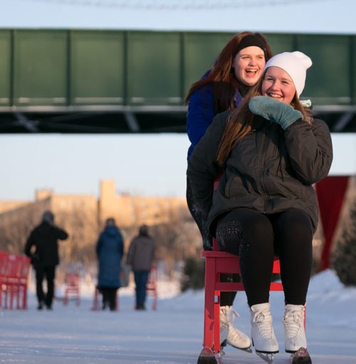 Visiting from North Dakota on a school trip, Kaitlyn Aarseth pushes her friend Atlanta Lehfeldt on the red chairs of the Recycling Words Warming Hut winner. Wednesday afternoon was -23C temperature and -30C windchill. 150218 - Wednesday, February 18, 2015 - (Melissa Tait / Winnipeg Free Press)