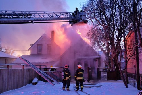 Firefighters work on extinguishing a fire that spread to two houses in the 600 block of Elgin Avenue Wednesday afternoon. 150218 February 18, 2015 Mike Deal / Winnipeg Free Press