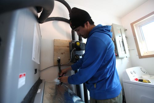 Lyle McKay a trained service technician from the community installs a geothermal furnace into a older home in the community.  Not only has the renewable energy source drastically cut residents heating bills but also has provided training and employment for residents.  Feature story on how sustainable energy sources like  geothermal and solar are being implemented on First Nation reserves like Peguis and Fisher River and its positive impact on the people and our province.   See Alex Paul story.   Feb 17, 2015 Ruth Bonneville / Winnipeg Free Press