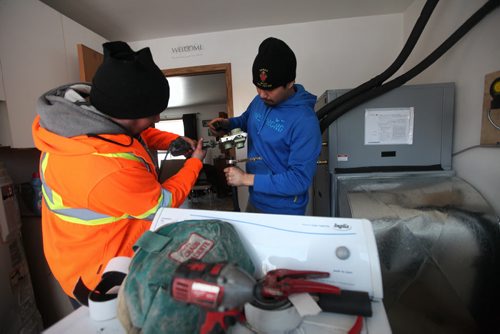 Lyle McKay (blue) and  Clayton Sinclair (orange) trained service technicians from the community install a geothermal furnace into a older home in the community.  Not only has the renewable energy source drastically cut residents heating bills but also has provided training and employment for residents.  Feature story on how sustainable energy sources like  geothermal and solar are being implemented on First Nation reserves like Peguis and Fisher River and its positive impact on the people and our province.   See Alex Paul story.   Feb 17, 2015 Ruth Bonneville / Winnipeg Free Press