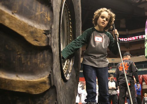 Eleven-year-old Ian Dyck who is visually impaired, explores the inside rim of  a tire on one of the monster trucks during a special touch tour for kids with vision loss Friday sponsored by Monster Truck Jam. Standup photo Feb 20, 2015 Ruth Bonneville / Winnipeg Free Press