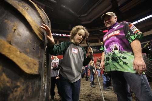 Eleven-year-old Ian Dyck who is visually impaired, explores the inside rim of  a tire on one of the monster trucks with driver Chad Tingler during a special touch tour for kids with vision loss Friday sponsored by Monster Truck Jam. Standup photo Feb 20, 2015 Ruth Bonneville / Winnipeg Free Press