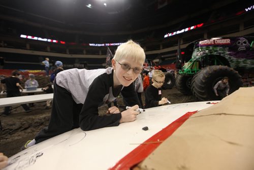 Nine-year-old Denly Katazin, who is visually impaired, writes his name and draws pictures on a car that will be later crushed during a special touch tour for kids with vision loss Friday sponsored by Monster Truck Jam. Standup photo Feb 20, 2015 Ruth Bonneville / Winnipeg Free Press