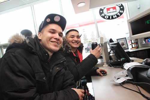 Ryan Moar (left) and Dallas McKinney (right)  both from Long Plain FN are all smiles after making purchases during the grand opening of the new Petro Canada gas station on Madison Street, Winnipeg's first urban reserve gas station.  150223 February 23, 2015 Mike Deal / Winnipeg Free Press