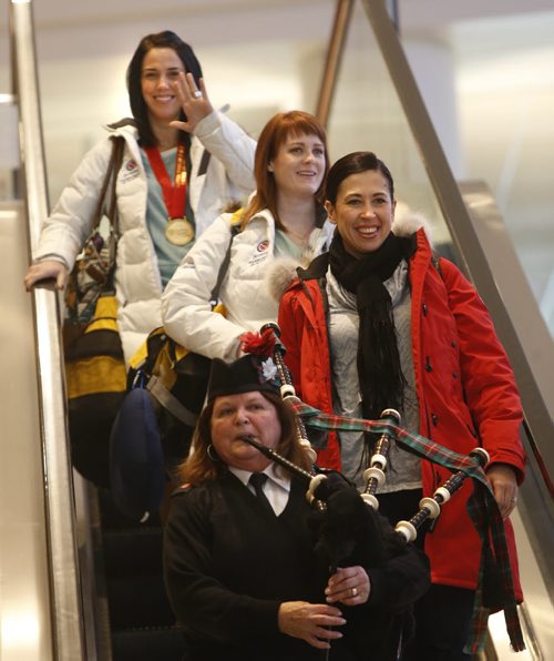 Three members of Team Jones from front , second Jill Officer,  lead Dawn McEwen and  alternate Jennifer Clark-Rouire arrive at James A Richardson International Airport Monday after the team won the Canadian championship in the Scotties Tournament of Hearts Sunday. They were piped down the escalator by Hilda Towerzey.   Wayne Glowacki/Winnipeg Free Press Feb.23   2015