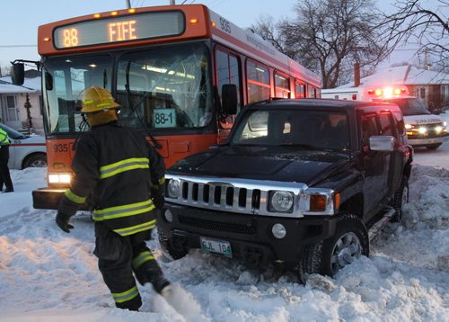 A Winnipeg Transit bus and a hummer collided this morning at the corner of Airles and Polson St.- The mishap ended up on the front yard of a home at the intersection_ 1 person was seen being loaded into a ambulance with injuries  Standup Photo- Feb 24, 2015   (JOE BRYKSA / WINNIPEG FREE PRESS)