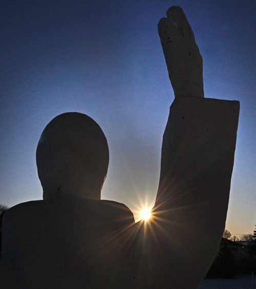 The sun rises Monday morning framed through a statue at the St Boniface cemetery on Archibald St  Standup Photo- Mar 02, 2015   (JOE BRYKSA / WINNIPEG FREE PRESS)