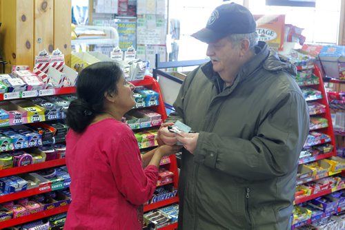 NEWS - Bergie's convenience store in Beausejour. Assault victim Tanu Mukherjee in the store on Monday morning. Here a local customer who didn't want to give his name gives Tanu support. BORIS MINKEVICH/WINNIPEG FREE PRESS MARCH 2, 2015
