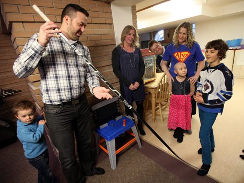 TJ Stroud, gives his Winnipeg Jets-signed hockey stick to Keaton Hamin (9), which he won at a previous event. TJ offered to replace a stick Keaton won then gave to leukemia patient, Alyx Delaloye (7)  (standing rear with her mom Jody, Keaton's Dad Ken peeks out from behind her) .  Allison Kesler CEO of Ronald MacDonald House Mb.stands in the middle. See Ashley Prest story. Maarch 4, 2015 - (Phil Hossack / Winnipeg Free Press)