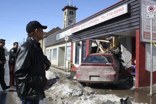 Julio Latigar looks at his demolished restaurant as police and fire crews prepare to pry a vehicle from the front window of Myrnas Café & Catering. The accident happened Sunday morning on Sargent Avenue. March 8, 2015. Jessica Bothelo-Urbanski / Winnipeg Free Press