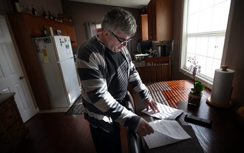 Zeljko Cupic reviews documents from city hall as his home rattles around him from work on the Plessis Underpass next to Paul Martin Drive. See Ashley Prest story. March 11, 2015 - (Phil Hossack / Winnipeg Free Press)