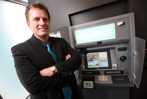 Kevin McKnight, CEO of Noventis Credit Union poses beside the province's first ITM. The "I" stands for "interactive."  When you go to the ATM, you press a button and are immediately hooked up via video with a teller at their headquarters in Gimli. From there, it's just like being in a branch. For example, you can withdraw any amount of money, not just in increments of $20 or $50. See Geoff Kirbyson's story. (March 12, 2015 - Phil Hossack / Winnipeg Free Press)