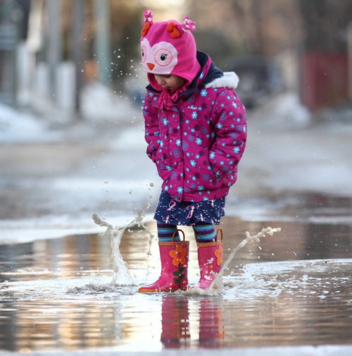 Three-year-old Hannah Braico enjoys stomping her rubber boots in the large puddles of water in the backlane behind their home in River Heights Friday afternoon while playing with her older sister Maddie as their father looks on.  (Dad and older sister not in photo).  March 13, 2015 Ruth Bonneville / Winnipeg Free Press.