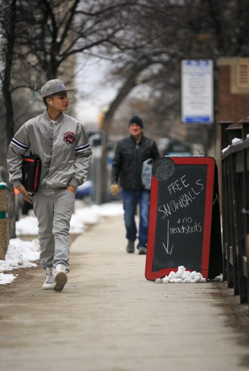 Darnell Hornbrook walks  past a cheeky chalk board sign by the  Army, Navy & Air Force (ANAF) Club 60 Monday on his way from school. 4-6 centimetres of snow fell Monday, much of it melting on the roads and sidewalks with the temperature just above freezing.   150323 - Monday, March 23, 2015 - (Melissa Tait / Winnipeg Free Press)