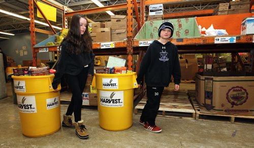 Matthew Kieper (right), 11, a student from Springfield Heights and Juliana Medeiros (left), 13, a student from Henry G Izatt Middle School, pull the bins full of donated food at Winnipeg Harvest after the announcement that 36 Manitoba Schools collected 7920kg of food during this years Operation Donation School Food Drive. The grand total for donations during the drive came to 57,277kg as other organizations like Safeway, MPI and Peak of the Market also contributed.  150324 March 24, 2015 Mike Deal / Winnipeg Free Press