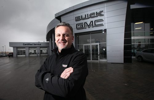 Jason Cross stands in front of Gauthier's Buick GMC dealership at Templeton and McPhillips. The newly re-clad dealership matches the Gauthier Chevrolet Dealership farther south on McPhillips. See story. March 24, 2015 - (Phil Hossack / Winnipeg Free Press)