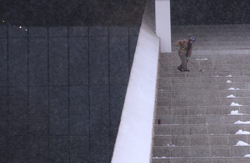 A worker clears wet snow away from joints on the steps of the Canadian Museum for Human rights Wednesday morning- Standup Photo- Mar 25, 2015   (JOE BRYKSA / WINNIPEG FREE PRESS)