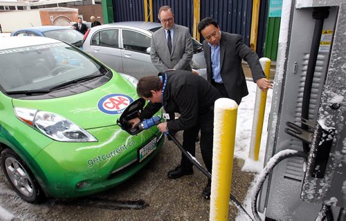 Ken Francis with CAA Manitoba plugs in his car while Jose Reyes (right) the research manager at RRC and Ray Hoemsen Director of Applied Research at RRC help out after the unveiling of the recently installed Level 3 (30KW DC) electric vehicle (EV) quick charging station at the RRC Notre Dame campus. This new charger can charge an EV car in about 30 mins and is the first of its kind in Manitoba. 150325 March 25, 2015 Mike Deal / Winnipeg Free Press