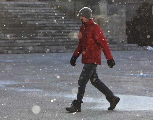 A pedestrian walks through lightly falling snow by the Manitoba Legislative Building Thursday morning.  150326 March 26, 2015 Mike Deal / Winnipeg Free Press