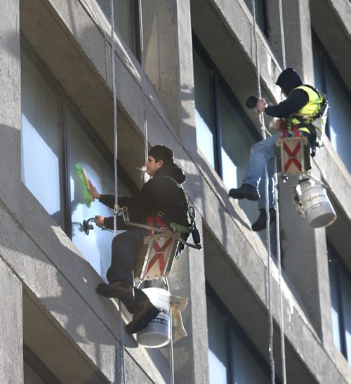 What's it like to be dangling over The Fairmont hotel on on sunny -7C morning? " I love it" says Chris Desjardin at left. "Calming, relaxing, the best job in the world" says Chris St. Germain at right, a window washer for 40 years. Wayne Glowacki/Winnipeg Free Press March 26 2015