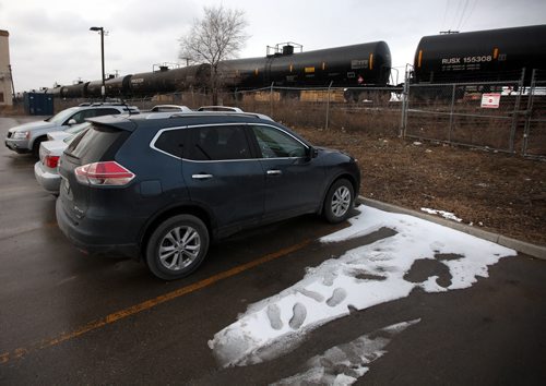 City center workers park cars adjacent to the rail yards and a train made up of oil tanker cars flowing through the city center. See story. March 27, 2015 - (Phil Hossack / Winnipeg Free Press)