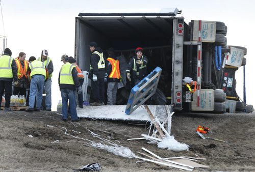 Produce is unloaded from an over turned semi-trailer on the Perimeter Hwy. near McGillvray Blvd. Monday morning after the vehicle rolled over at aprox. 1:30A.M. The 45-year-old male driver was not injured in the collision.Wayne Glowacki/Winnipeg Free Press March 30 2015