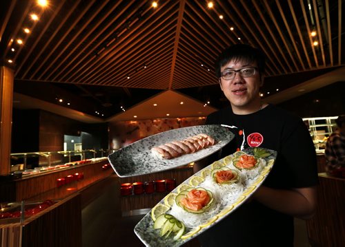 Ye's Buffet on St. James St. Restaurant Review. Manager Ivan Tang holds a plate in foreground with Salmon Sashimi and Smoked Salmon in centre. On plate at left is Grilled Salmon Sushi. Marion Warhaft  story Wayne Glowacki/Winnipeg Free Press April 1 2015