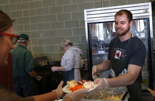 Volunteer Jason Kasala hands over another meal to a server at the annual Agape Table  Easter meal of turkey and ham that was served Thursday morning.  People attending also received a donated gift. As many as 450 guests were expected for the special meal.  Agape Table is also celebrating it's 35th anniversary. Wayne Glowacki/Winnipeg Free Press April 2 2015