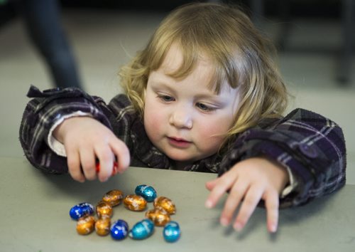 150405 Winnipeg - DAVID LIPNOWSKI / WINNIPEG FREE PRESS  Ella Symaka (age 2) collects her chocolate eggs Sunday April 5, 2015 after taking part in the Royal Aviation Museum of Western Canada's Easter Egg Hunt. About 500 people came out on Sunday to participate.