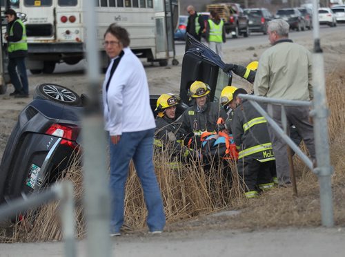 Firefighters extract an occupant of a vehicle that rolled into a ditch after colliding with a "First Canada"  bus on Main Street  north of River Grove Thursday afternoon. April 9, 2015 - (Phil Hossack / Winnipeg Free Press)