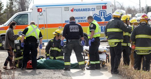 Firefighters and paramedics tend to the occupant of a vehicle that rolled into a ditch after colliding with a "First Canada"  bus on Main Street  north of River Grove Thursday afternoon. April 9, 2015 - (Phil Hossack / Winnipeg Free Press)