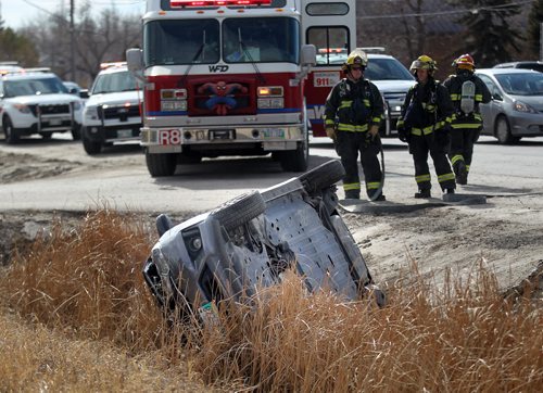 Firefighters oversee a vehicle that rolled into a ditch after colliding with a "First Canada"  bus on Main Street  north of River Grove Thursday afternoon. April 9, 2015 - (Phil Hossack / Winnipeg Free Press)