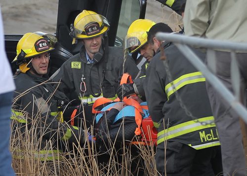 Firefighters extract an occupant of a vehicle that rolled into a ditch after colliding with a "First Canada"  bus on Main Street  north of River Grove Thursday afternoon. April 9, 2015 - (Phil Hossack / Winnipeg Free Press)
