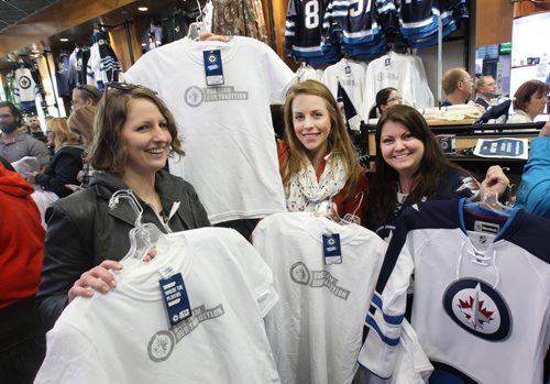 White Out Frenzy- L to R -Jets fans Lindsay Wareham, Rebecca Bowswell and Inga Hossack snagged a pile of white Jets shirts and jerseys at the Jets Gear store at the MTS Centre Friday morning- The Jets secured a Stanley Cup playoff spot yesterday and over 300 fans lined up for the opening of the store -See Geoff Kirybson story- Apr 10, 2015   (JOE BRYKSA / WINNIPEG FREE PRESS)