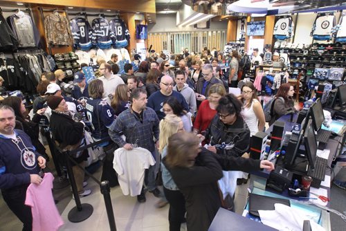 White Out Frenzy- L to R -Jets fans scramble to grab white Jets jerseys and t-shirts at the Jets Gear store at the MTS Centre Friday morning - The Jets secured a Stanley Cup playoff spot yesterday and over 300 fans lined up for the opening of the store -See Geoff Kirybson story- Apr 10, 2015   (JOE BRYKSA / WINNIPEG FREE PRESS)