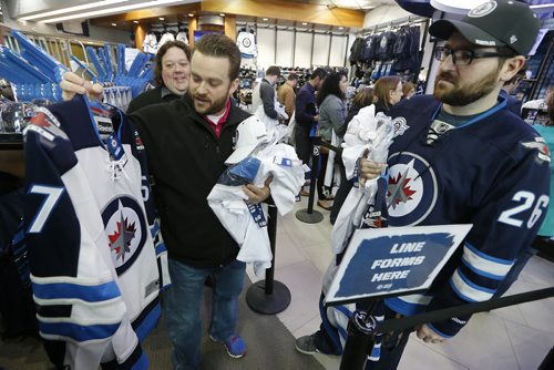 Bobby Launderville (L) and Travis Paskaruk check out their new white Winnipeg Jets jerseys as they wait to pay at the Jets Gear store in Winnipeg, Friday, April 10, 2015. Thousands of Winnipeg Jets fans lined up to get their hands on some white Jets merchandise after a "whiteout" was announced for their  team's home NHL playoff games.   THE CANADIAN PRESS/John Woods