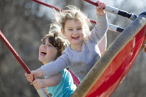 Three-year-old Madalyn Park (front, grey), five-year-old Rena Bedder (blue) and Vivian Flemington, 4yrs (in rear, pink), laugh and giggle in the warm sunshine together as they get pushed on a large swing at The Nature Playground at Assiniboine Park Friday.  Standup photo April 10, 2015 Ruth Bonneville / Winnipeg Free Press.