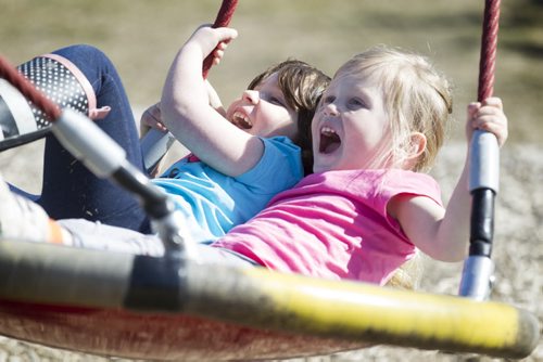 Five-year-old Rena Bedder (blue) and Vivian Flemington, 4yrs  (pink), laugh and giggle in the warm sunshine together as they get pushed on a large swing at The Nature Playground at Assiniboine Park Friday.  Standup photo April 10, 2015 Ruth Bonneville / Winnipeg Free Press.