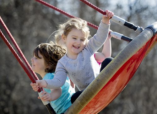 Three-year-old Madalyn Park (front, grey), five-year-old Rena Bedder (blue) and Vivian Flemington, 4yrs (in rear, pink), laugh and giggle in the warm sunshine together as they get pushed on a large swing at The Nature Playground at Assiniboine Park Friday.  Standup photo April 10, 2015 Ruth Bonneville / Winnipeg Free Press.
