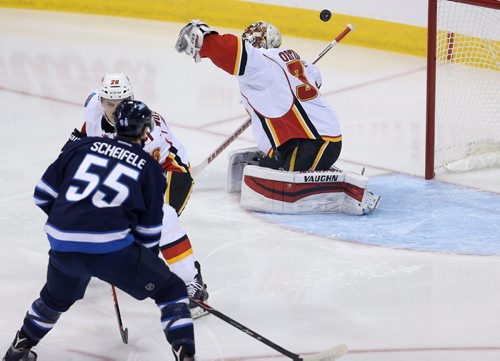 Winnipeg Jets' Drew Stafford (12) has his shot bounce off the head of Calgary Flames' Joni Ortio (37) before going in the net during NHL hockey action, Saturday, April 11, 2015. (TREVOR HAGAN/WINNIPEG FREE PRESS)