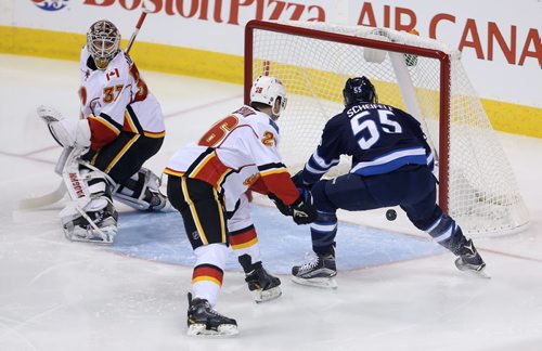 Winnipeg Jets' Drew Stafford (12), not shown, has his shot bounce off the head of Calgary Flames' Joni Ortio (37) before going in the net with Flames' Tyler Wotherspoon (26) and Jets' Mark Scheifele (55) in front, during NHL hockey action, Saturday, April 11, 2015. (TREVOR HAGAN/WINNIPEG FREE PRESS)