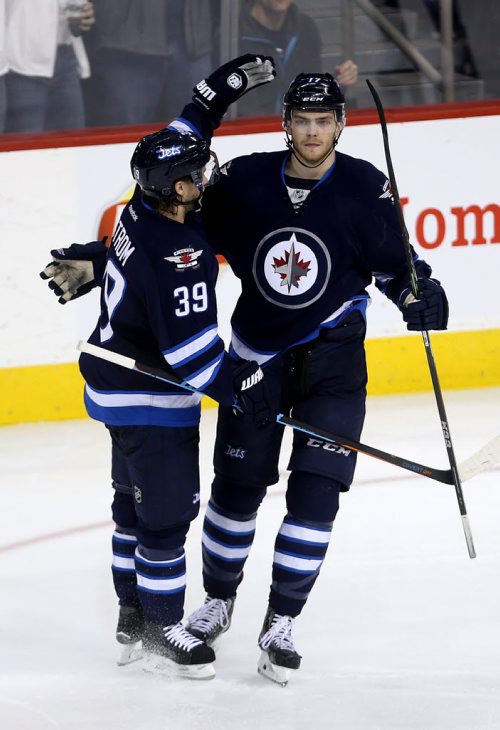 Winnipeg Jets' Toby Enstrom (39) and Adam Lowry (17) celebrate after Lowry scored against the Calgary Flames' during third period NHL hockey action, Saturday, April 11, 2015. (TREVOR HAGAN/WINNIPEG FREE PRESS)