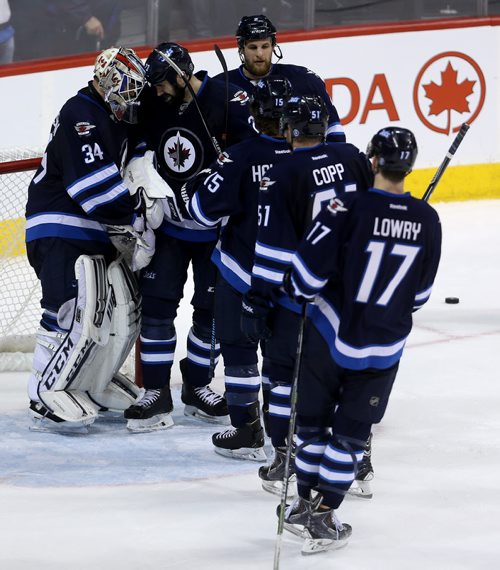 The Winnipeg Jets' congratulate goaltender Michael Hutchinson (34) after the team's victory against the Calgary Flames' during NHL hockey action, Saturday, April 11, 2015. (TREVOR HAGAN/WINNIPEG FREE PRESS)