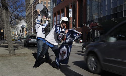 Winnipeg Jets fans Tyler Macfarlane (front) and Cody Laschyn, wave a Jets banner and a blow-up Stanley Cup on Portage Ave, to drivers passing by them in celebration of the Jets heading into the playoffs Saturday afternoon.   Ruth Bonneville / Winnipeg Free Press March 26, 2015