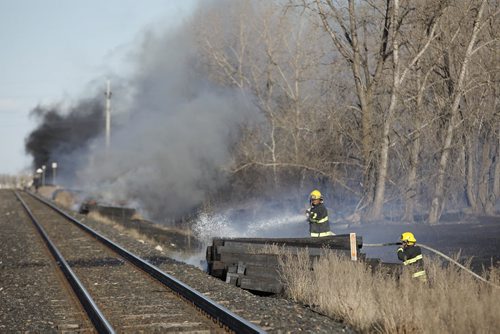April 13, 2015 - 150413  -  Firefighters attend to a grass and railway tie fire along the tracks and Wilkes Avenue  Monday, April 13, 2015.  John Woods / Winnipeg Free Press