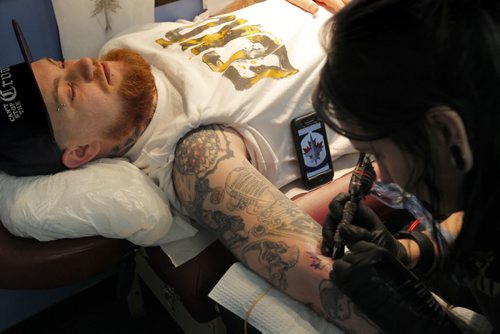 JETS TATTOO - (right) South of Heaven Tattoo artist Karen Melia puts a Winnipeg Jets tattoo on Lawrence Lavallee.  BORIS MINKEVICH/WINNIPEG FREE PRESS APRIL 15, 2015