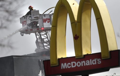 Winnipeg Firefighters hose down a blaze at MacDonalds restraunt in the 900 block of Henderson Highway Wednesday afternoon. Spectators speculated the blaze started when wind blew sparks from an outdoor ashtray ignighting the blaze. See story. April 15, 2015 - (Phil Hossack / Winnipeg Free Press)