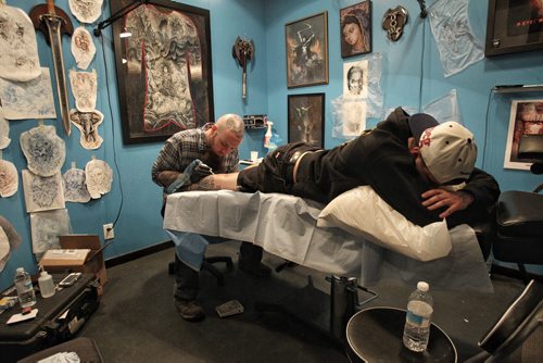 Chad Fabian gets a Winnipeg Jets tattoo applied to one of his calves Wednesday night by artist Dave Nazgul at 13th Hour Tattoo.  150415 April 15, 2015 Mike Deal / Winnipeg Free Press